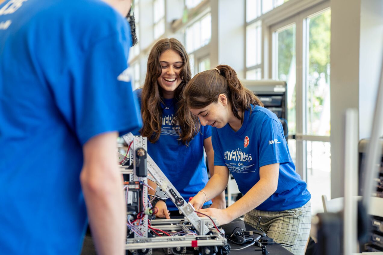 CIS team members make adjustments to their robot